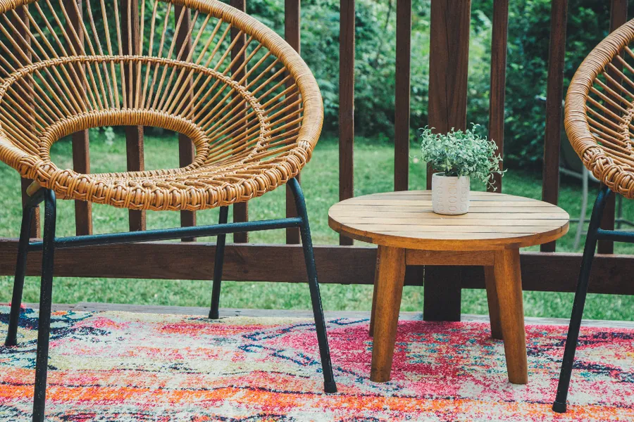 Wooden deck with a railing and patio chairs overlooking trees